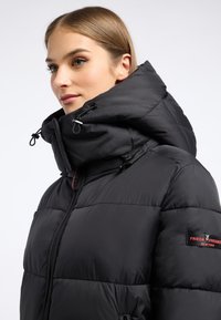 Czarna kurtka puchowa z wysokim kołnierzem i sznurkiem. Posiada pikowany wzór, zamki błyskawiczne oraz naszywkę z logo na rękawie. Gładka faktura.