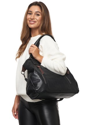 Zwarte leren handtas met bruine accenten, grote maat, twee voorvakritsen, slouchy ontwerp, vastgehouden door een persoon in een witte trui.