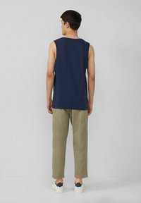 Navy sleeveless top made of soft fabric, paired with light khaki trousers, featuring a relaxed fit and minimalistic design. White sneakers.