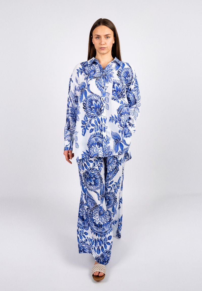 Blumenmuster-Outfit bestehend aus einem blauen und weißen Langarmhemd und passenden Hosen, gefertigt aus einem leichten Stoff mit lockerer Passform.