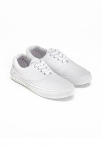 Sneakers bianchi in tela con design lacciato, suola in gomma testurizzata e punta rotonda. Stile minimalista senza motivi o accenti.