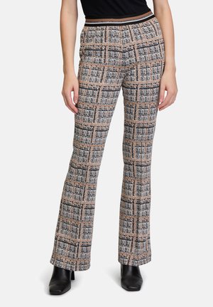 Pantaloni dritti a scacchi in beige, nero e arancione. Presentano un tessuto testurizzato e una cintura elasticizzata. Indossati con stivaletti neri.