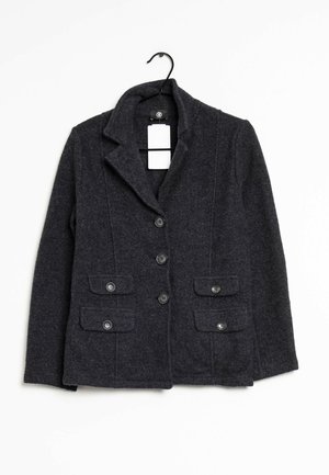 Dark gray buttoned wool blazer with notched lapel collar and four front flap pockets, hanging on a black hanger with a white tag.