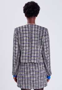 Blazer- und Rock-Set aus strukturiertem, mehrfarbigem Gewebe mit einem karierten Muster in Blau und Weiß, langen Ärmeln und einer taillierten Silhouette.