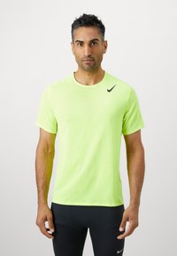 Jasnożółta, krótko rękawowa koszulka sportowa z oddychającą strukturą, z czarnym logo Nike na lewym ramieniu.