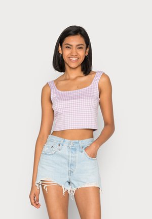 Top de gingham roxo e branco, com alças largas, combinado com calções de denim rasgados de cintura alta, apresentando bordas desfiadas.