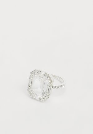 Bague en argent avec une grande pierre précieuse rectangulaire claire entourée de petites pierres rondes et baguette claires sur un fond blanc uni.