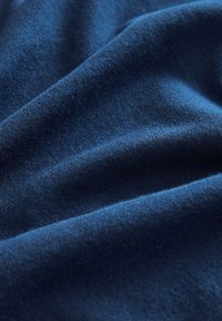 Zils kokvilnas audums ar mīkstu faktūru, kurā redzami maigi krokas un gluda virsma. Krāsa ir vienmērīga visā platībā, bez rakstiem.