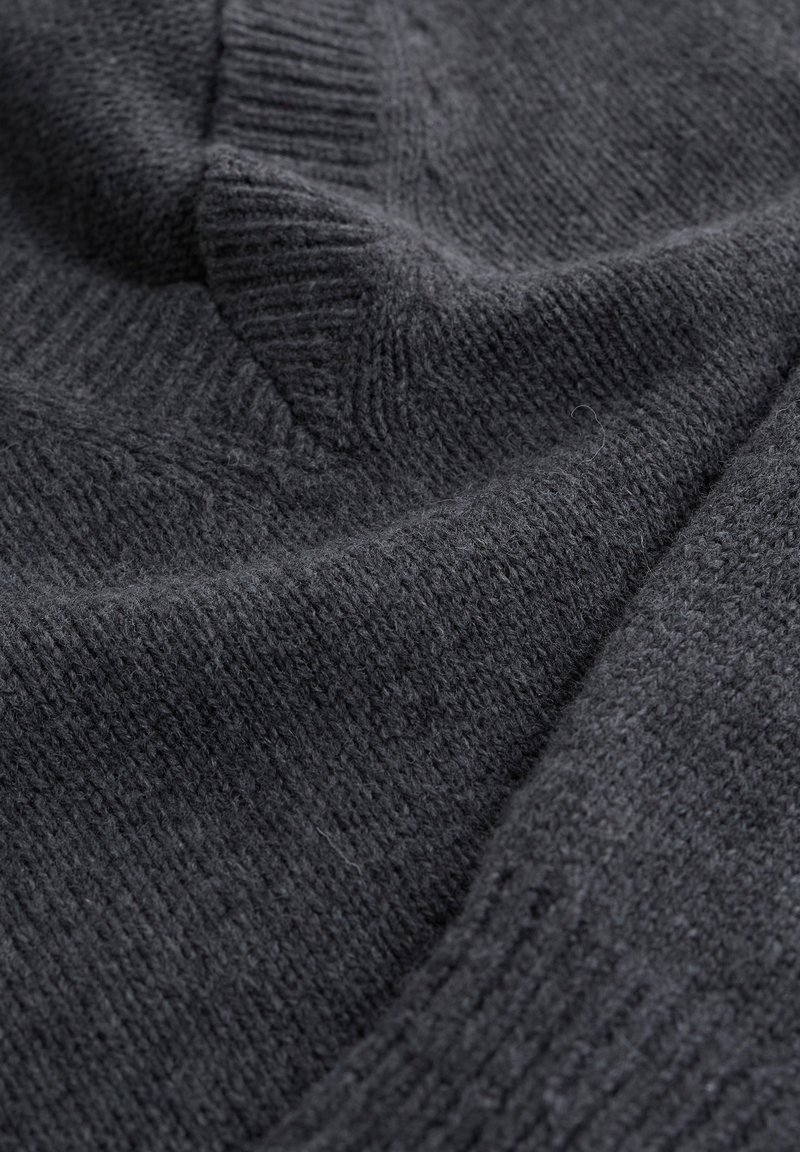 Donkergrijze gebreide trui met een gestructureerde afwerking, voorzien van geribde manchetten en een geribde zoom, met zachte, fijne vezels.