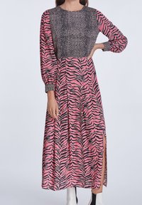 Langes Kleid mit einem schwarz-pinken Tigerstreifenmuster, einem strukturierten Oberteil und langen Ärmeln sowie einem seitlichen Schlitz für zusätzliche Details.