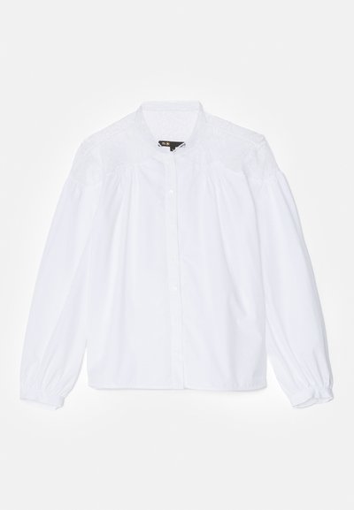 Hvit bluse med høy krage, knappelukking og voluminøse lange ermer med elastiske mansjetter og blonde detaljer på skuldrene.