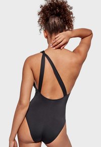 Traje de baño de una pieza negro, con un corte alto en la espalda, tirantes cruzados y una textura de tela suave, diseñado para una silueta ajustada.
