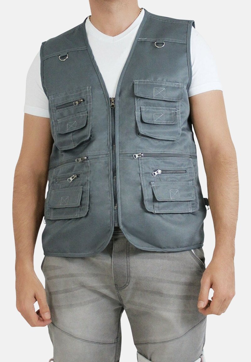 Gilet utilitaire gris en tissu avec plusieurs poches, fermeture éclair à l'avant et anneaux en métal. Conçu avec une coupe droite et sans manches.