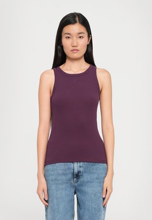 Lilla ribbet tanktop med rund hals og racerback-design. Har en subtil logo på brystet og passer godt med lyseblå denim.