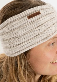 Fascia lavorata a maglia di colore grigio chiaro con texture a costine e un'etichetta in pelle. Materiale morbido con un design avvolgente e ampio che copre le orecchie.