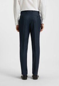 Marinblå skräddarsydda byxor med en strukturerad tyg, med platt front, två bakfickor och en tapered passform.
