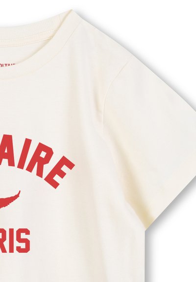 Camiseta de algodón color crema con un atrevido texto gráfico rojo que dice "PARÍS" y "CLAIRE", con un ícono de ala estilizado encima del texto.