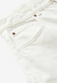Vita denimjeans med en subtil ribbad textur, utrustade med kopparfärgade detaljer och en klassisk fickdesign bak.