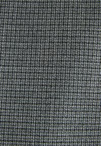 Textúrovaná látka tmavosivej farby so vzorom mriežky. Materiál pôsobí tkaný s kontrastnými svetlejšími niťami, ktoré vytvárajú jemný vizuálny záujem.