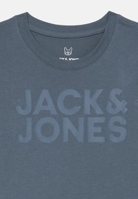 Temno modra bombažna majica s krožnim izrezom in velikim toniranim napisom "JACK & JONES" natisnjenim spredaj.
