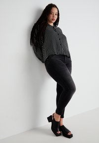 Black and white striped button-up shirt, black skinny jeans, and chunky black open-toe heels, with textured fabric and tailored fit.