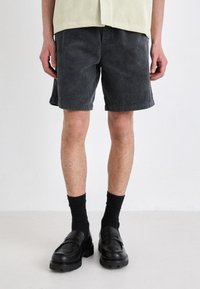 Gray corduroy shorts with a textured finish, featuring a relaxed fit and rolled hems, paired with black loafers and crew socks.