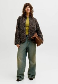 Brun leopardmønstret fleecejakke, grønn topp, høytlivs lys vaskede jeans og brun veske. Avslappet passform med vide ben og teksturert stoff.