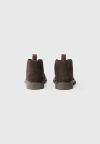 Brown suede ankle boots with a smooth finish, featuring a rounded toe, low rubber heel, and fabric pull tab at the back.