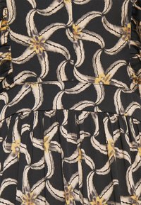 Robe en tissu noir ornée d'un motif détaillé de feuilles de bananier aux teintes claires avec des accents jaunes, plis texturés à la taille.