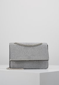 Borsa a borsa sintetica grigia con superficie testurizzata, tracolla in catena argentata e chiusura a pattina elegante con accentuazione metallica. Forma rettangolare.