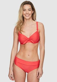 Korallfärgad bikini med knuten topp och justerbara band, tillsammans med högmidjade underdelar. Slätt tyg, minimalistisk design.