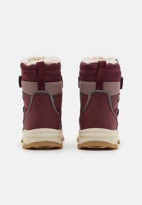 Botas impermeables color burdeos con un suave forro de pelo, acentos beige en contraste, suela de goma resistente y correas ajustables en la parte posterior.