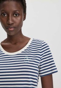 Marineblaues und weiß gestreiftes T-Shirt mit einem runden Ausschnitt und kurzen Ärmeln, das ein kleines hellblaues Herz-Stickerei auf der Brust aufweist.