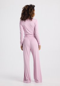 Light pink loungewear set consisting of a long-sleeve top and wide-leg pants. Made of soft, stretchy fabric with a relaxed fit.
