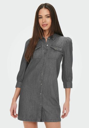 Grå denimklänning med knappstängning, två bröstfickor och ärmar som slutar vid armbågen. Har en figursydd midja och en något utsvängd fåll.