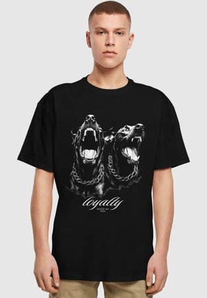Sort t-shirt med to grafiske, snerrende hunde med kæder, trykt i sort-hvid. Teksten "loyalty inside my DNA" er fremtrædende placeret nedenfor.
