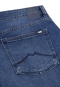 Donkerblauwe spijkerbroek van denim met een gestructureerde afwerking, voorzien van een achterzak met een gebogen stikselpatroon en een merketiket.