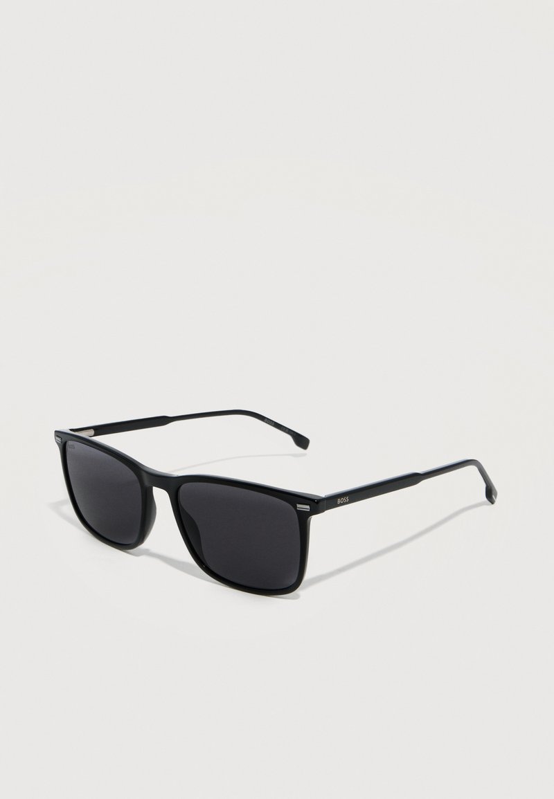Μαύρα ορθογώνια γυαλιά ηλίου με σκουρόχρωμους φακούς, λεπτά πλαίσια και λογότυπο "BOSS" στον βραχίονα, τοποθετημένα σε απλό ανοιχτό φόντο.
