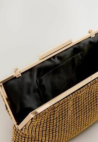 Guldprydet clutch-taske med en metallisk ramme, sort satininteriør og inderlomme. Den har en glat overflade og funkende detaljer.