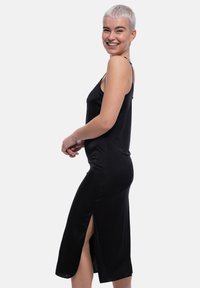 Abito nero senza maniche con una silhouette aderente e spacchi laterali, realizzato in tessuto morbido. Caratterizzato da spalline sottili e un design fino al ginocchio.