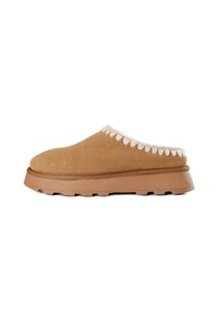 Chaussure marron en daim à enfiler avec une tige texturée, ornée de coutures décoratives beige le long du bord et d'une semelle en caoutchouc épaisse.