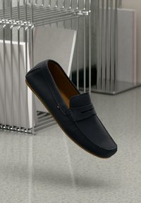 Sort læderloafer med en glat finish, rund tå og subtile syninger; har en lys brun gummisål.