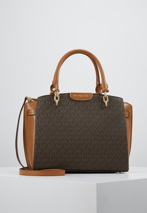 Brązowa torebka Michael Kors z monogramem, rączkami w kolorze jasnobrązowym, złotym okuciem i odpinanym paskiem na ramię, umieszczona na białej powierzchni.
