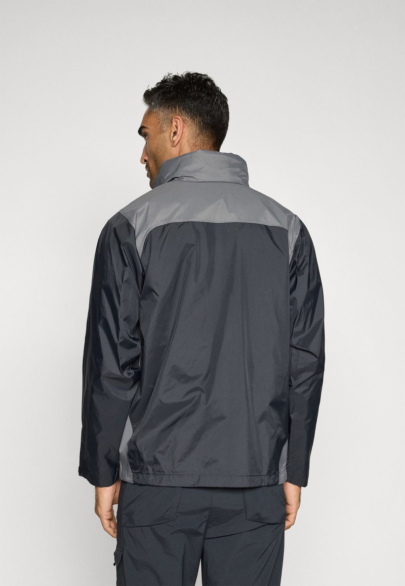 Chaqueta resistente al agua con un cuerpo gris oscuro y un panel de hombro gris más claro. Presenta un cuello alto y una textura suave y brillante.