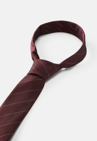 Μπορντό γραβάτα από λείο ύφασμα, με λεπτές λευκές διαγώνιες ρίγες και σχεδίαση με κόμπο, που παρουσιάζει κλασικό κομψό σχήμα.
