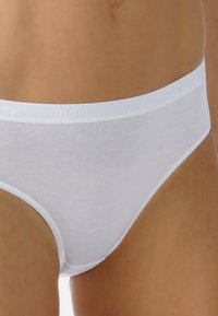 Mutande bianche in cotone con una texture liscia, caratterizzate da una morbida fascia elastica con il nome del marchio discretamente impressa. Taglio classico a slip.