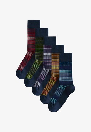 Fem par marineblå sokker arrangeret i en række, hver med et forskelligt stribet farvemønster på ben- og fodområderne.