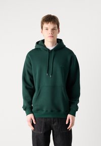 Sudadera verde oscuro de mezcla de algodón, que cuenta con un bolsillo frontal, capucha con cordón ajustable y un sutil branding en el pecho.
