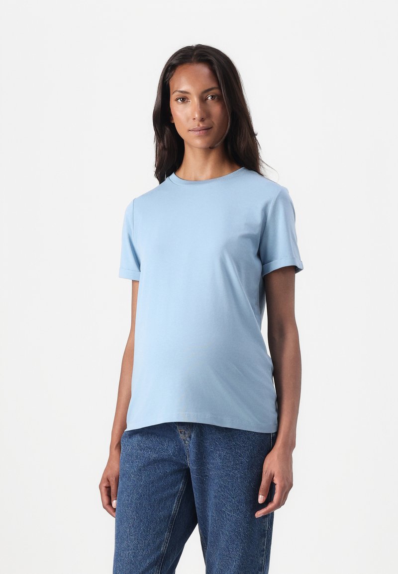 Tricou scurt, de culoare albastru deschis, dintr-un material moale, cu decolteu rotund, purtat cu blugi cu talie înaltă. Design simplu și curat.