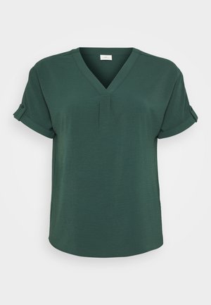 Blouse verte à manches courtes avec un décolleté en V, texture subtile et manchons roulés. Présente un pli central pour un détail supplémentaire.